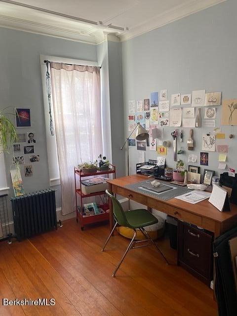 home office with hardwood / wood-style floors, crown molding, and radiator heating unit