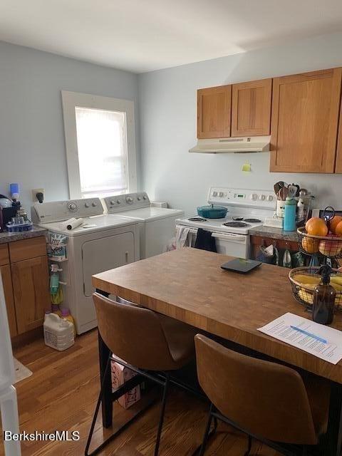 kitchen featuring electric stove, wood-type flooring, and separate washer and dryer