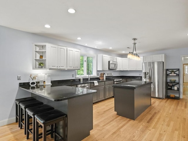 200 Newtown Rd, Acton, MA 01720 - kitchen featuring stainless steel appliances, a peninsula, a kitchen breakfast bar, light wood-type flooring, and white cabinets