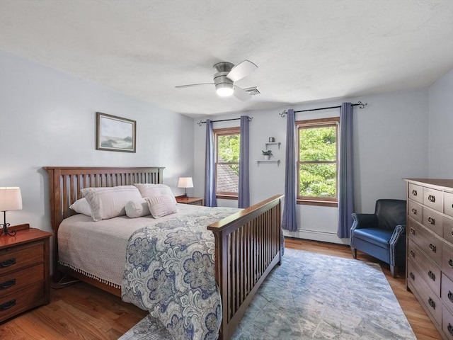 200 Newtown Rd, Acton, MA 01720 - bedroom with light wood finished floors, a baseboard heating unit, and a ceiling fan