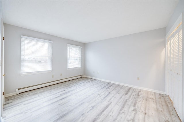 empty room with light hardwood / wood-style flooring and a baseboard heating unit