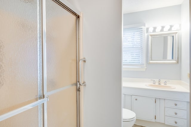 bathroom with vanity, a shower with shower door, and toilet