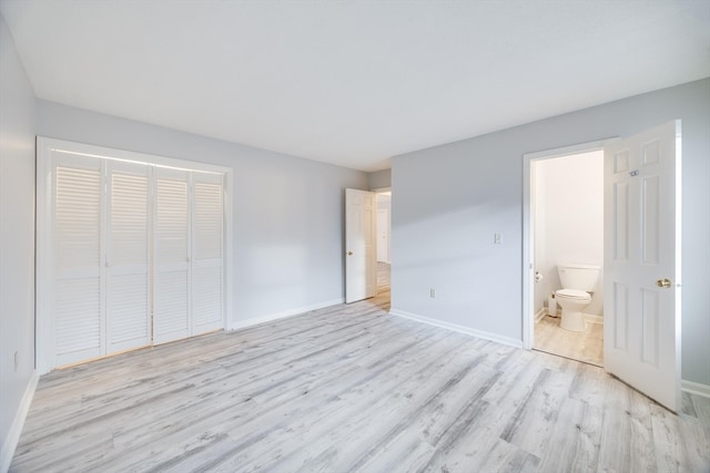 unfurnished bedroom featuring ensuite bath, light hardwood / wood-style floors, and a closet