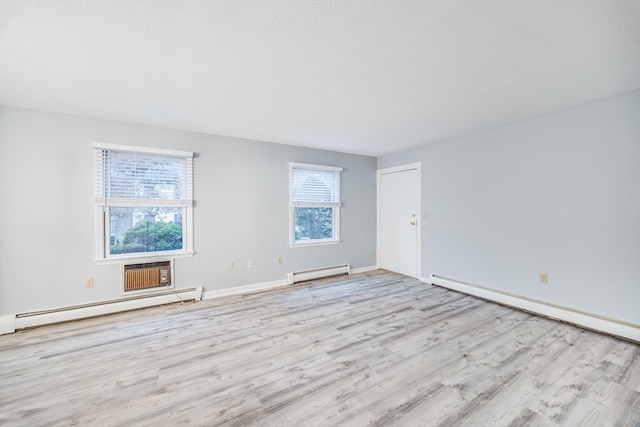 empty room with baseboard heating and light hardwood / wood-style flooring