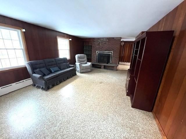 living room with a baseboard radiator, a fireplace, and wood walls