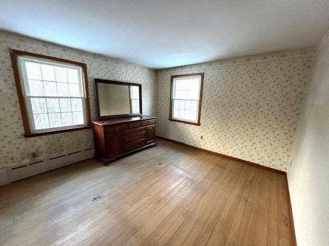 spare room featuring a baseboard heating unit and light wood-type flooring