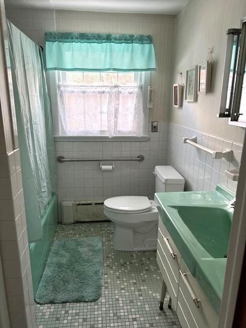 full bathroom with baseboard heating, tile walls, tile patterned flooring, vanity, and toilet