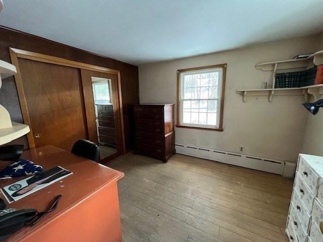 home office with a baseboard heating unit and light hardwood / wood-style flooring