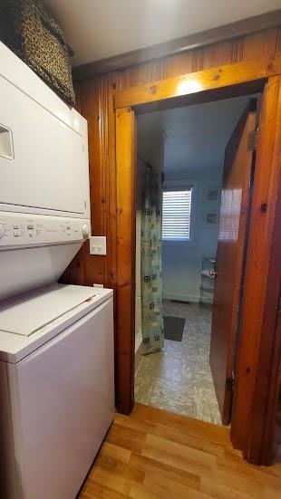 clothes washing area with laundry area, light wood finished floors, and stacked washing maching and dryer