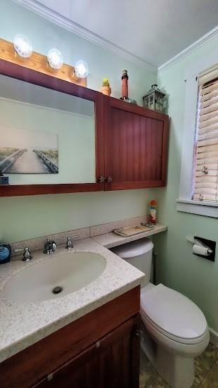 bathroom featuring toilet, ornamental molding, and vanity