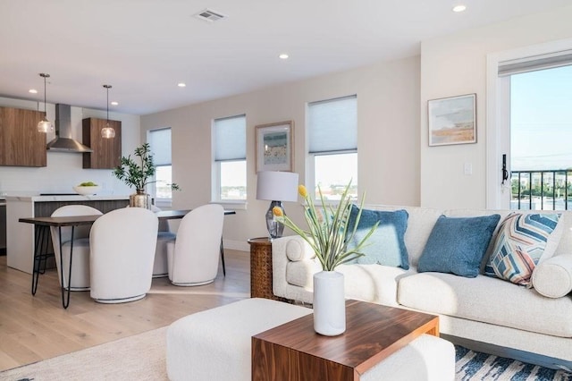 living room featuring light wood-type flooring, visible vents, and recessed lighting