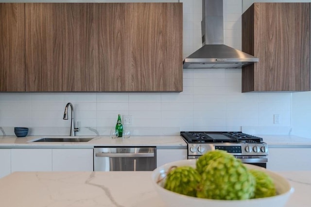 kitchen with appliances with stainless steel finishes, a sink, wall chimney exhaust hood, and modern cabinets