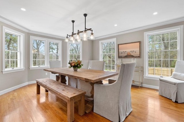 dining space with light wood-style floors, baseboards, ornamental molding, and a wealth of natural light