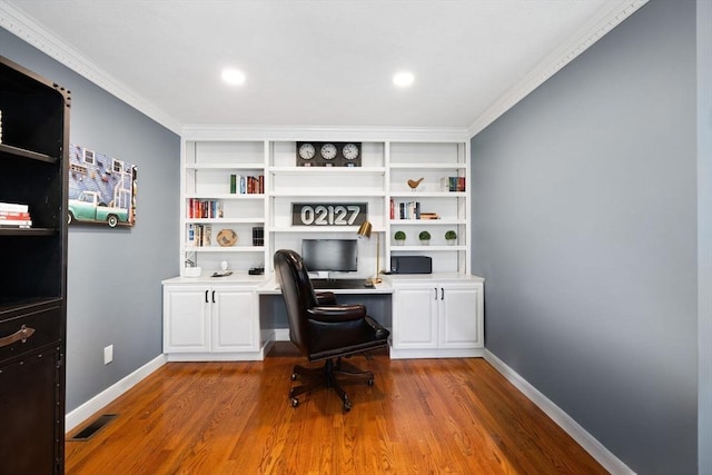 home office with baseboards, ornamental molding, wood finished floors, and visible vents