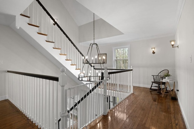 stairway featuring baseboards, crown molding, a chandelier, and hardwood / wood-style floors