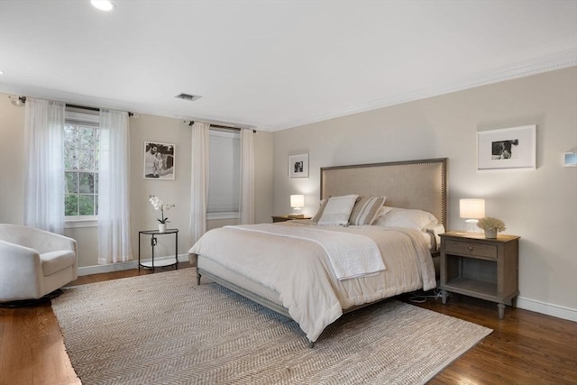 bedroom with visible vents, crown molding, wood finished floors, baseboards, and recessed lighting