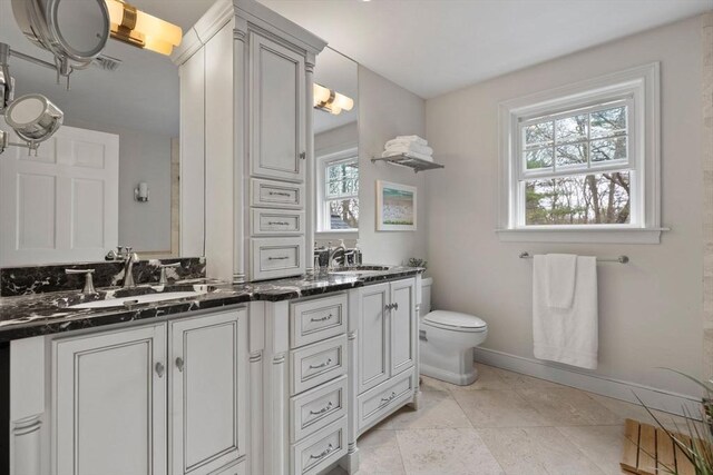 full bathroom with double vanity, a sink, baseboards, and toilet