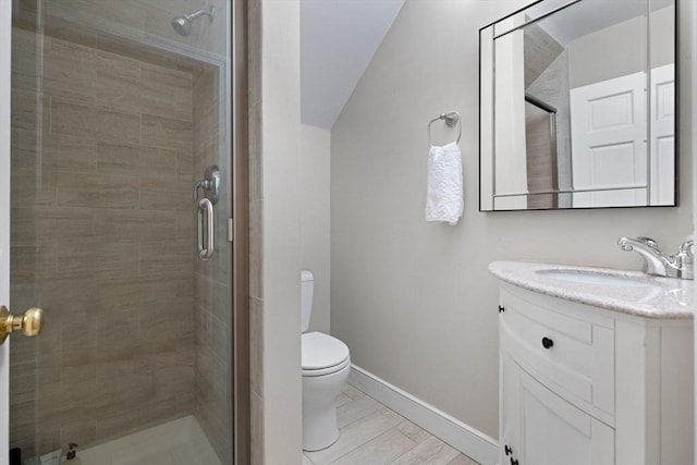 bathroom with vanity, baseboards, a stall shower, and toilet