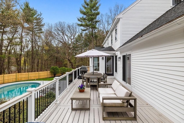 wooden deck featuring a fenced backyard, a fenced in pool, outdoor dining space, and area for grilling