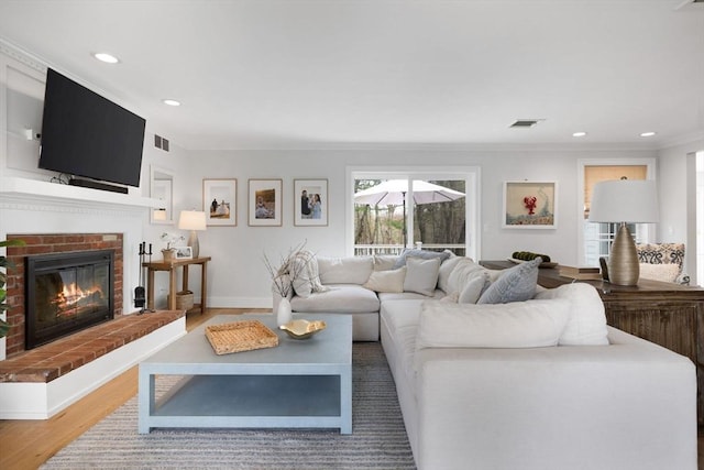 living room with crown molding, recessed lighting, visible vents, and wood finished floors