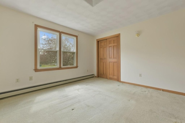 carpeted spare room with baseboards, a baseboard heating unit, and visible vents
