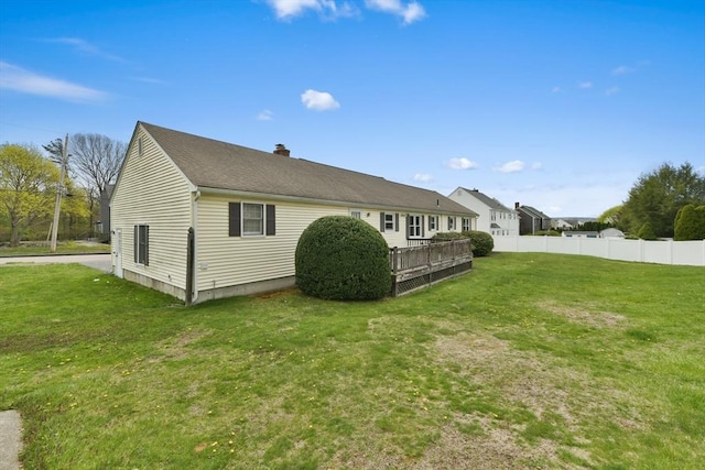 view of side of home with a lawn, fence, and a chimney