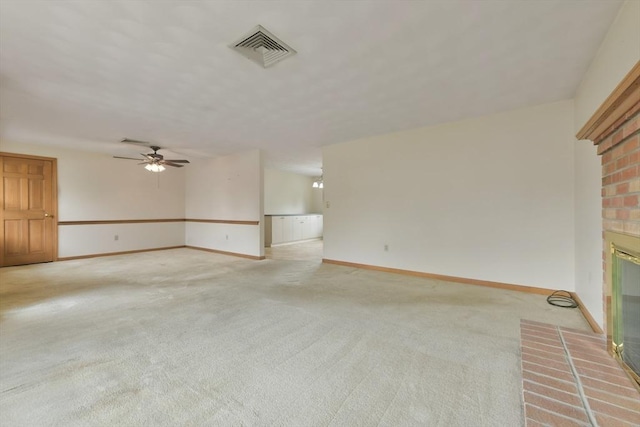 unfurnished living room with light colored carpet, a fireplace, a ceiling fan, baseboards, and visible vents