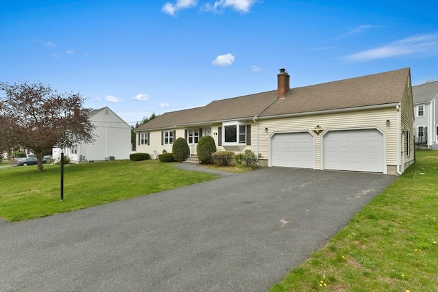 ranch-style house with an attached garage, driveway, a chimney, and a front lawn