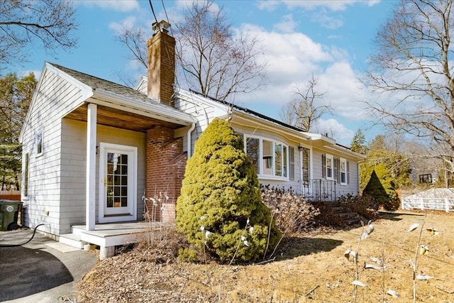 exterior space with driveway, brick siding, and a chimney