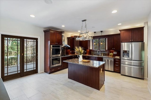 kitchen featuring appliances with stainless steel finishes, dark stone counters, sink, a center island, and hanging light fixtures