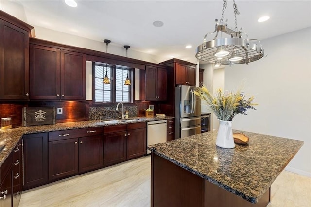 kitchen featuring a center island, sink, stainless steel refrigerator with ice dispenser, dark stone countertops, and dishwashing machine