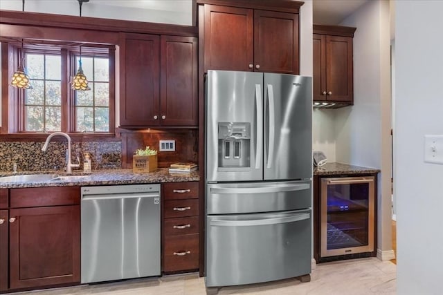 kitchen with stainless steel appliances, wine cooler, dark stone counters, and sink