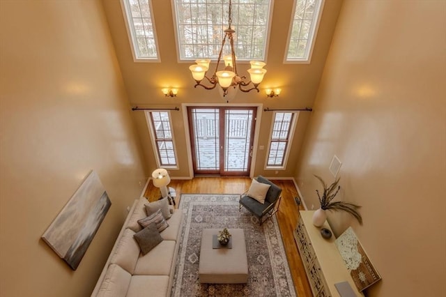 living room with hardwood / wood-style floors, a high ceiling, and a chandelier