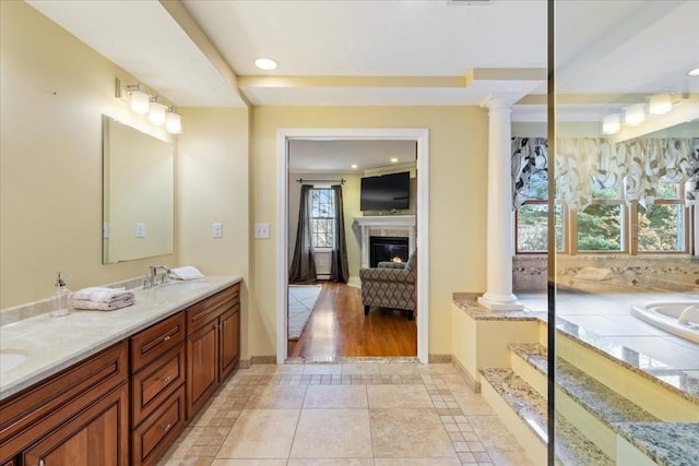 bathroom featuring vanity, tile patterned flooring, a washtub, a premium fireplace, and decorative columns