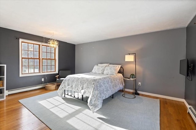 bedroom with an inviting chandelier, baseboard heating, and light hardwood / wood-style flooring