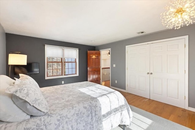 bedroom with an inviting chandelier, wood-type flooring, and a closet