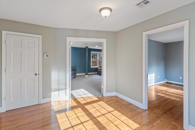 unfurnished room featuring baseboard heating and hardwood / wood-style flooring