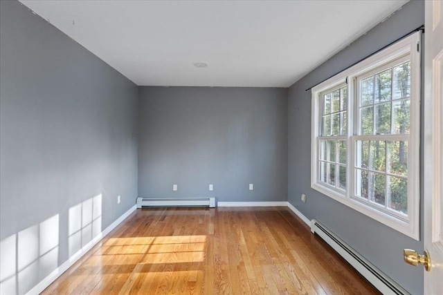 empty room with light hardwood / wood-style flooring and a baseboard heating unit