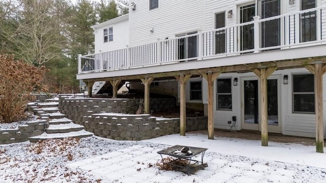 snow covered back of property featuring a deck and an outdoor fire pit