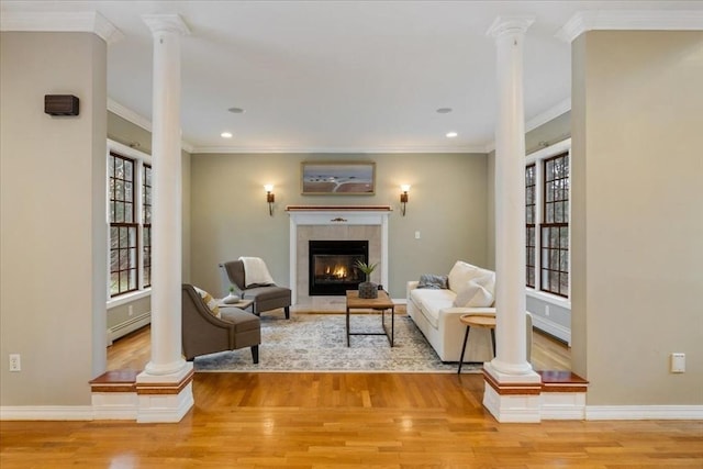 living room featuring a tile fireplace, light hardwood / wood-style flooring, a healthy amount of sunlight, and ornamental molding