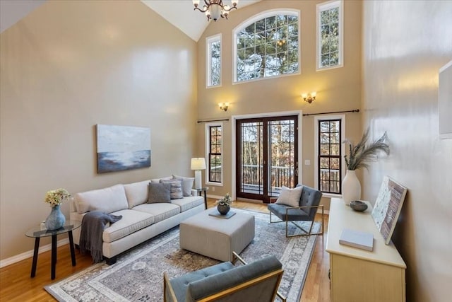 living room featuring a healthy amount of sunlight, light hardwood / wood-style floors, a towering ceiling, and an inviting chandelier