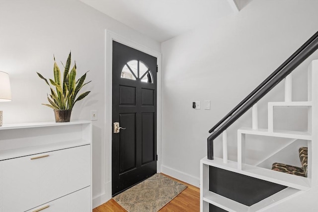 foyer featuring light wood-type flooring, baseboards, and stairs