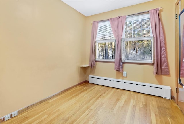 unfurnished room featuring baseboard heating and hardwood / wood-style floors