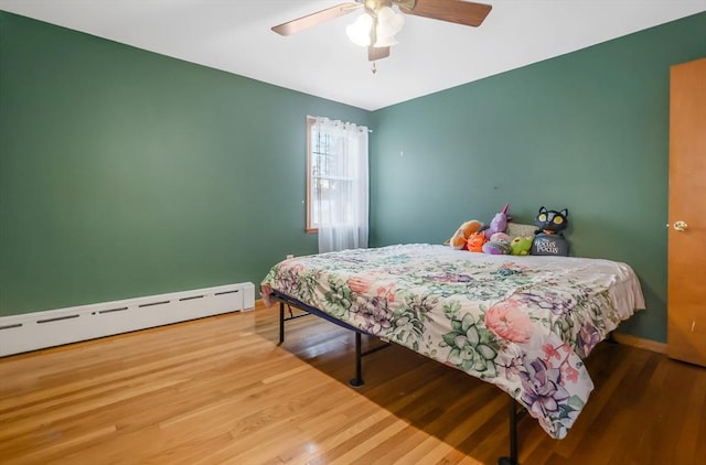 bedroom featuring hardwood / wood-style flooring, ceiling fan, and baseboard heating