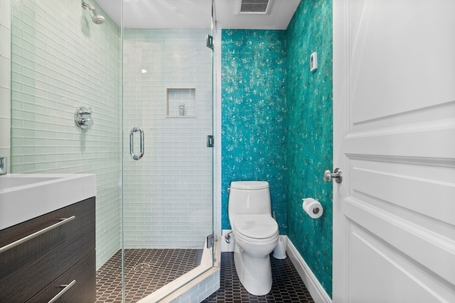 bathroom featuring vanity, toilet, walk in shower, and tile patterned flooring