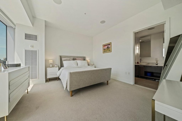 bedroom with connected bathroom, sink, and light colored carpet