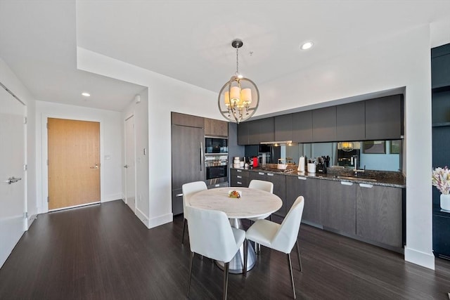 dining space with a chandelier, sink, and dark wood-type flooring