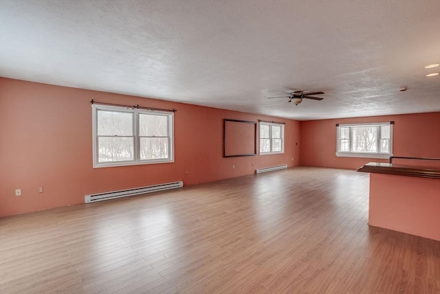 unfurnished living room with baseboard heating, light hardwood / wood-style flooring, a textured ceiling, and ceiling fan