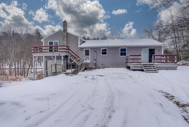 snow covered rear of property with a deck