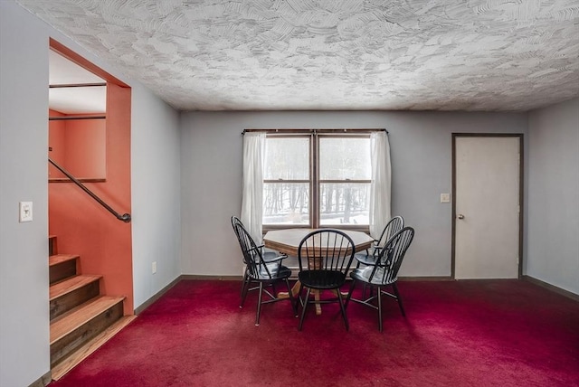 carpeted dining room with a textured ceiling